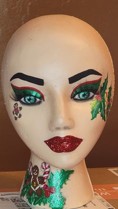 a white mannequin head with christmas decorations painted on it's face and eyes