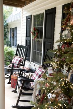 the porch is decorated for christmas with rocking chairs