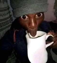 a person sticking their tongue out while holding a coffee cup in front of his face