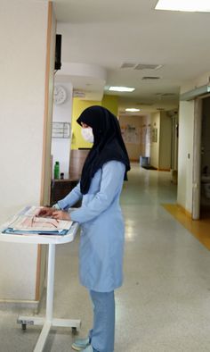 a woman in a hijab is standing at a table with a poster on it