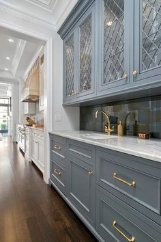 a kitchen with gray cabinets and gold handles on the countertops, along with hardwood floors