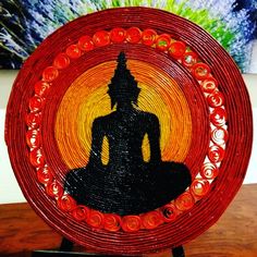 a red and black plate with a buddha image in the center on a wooden table