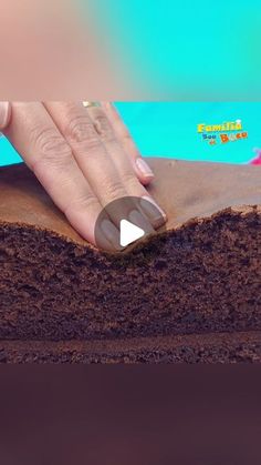 a woman's hand on top of a piece of cake with chocolate frosting