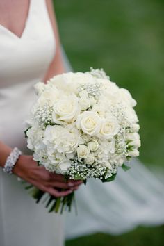 a bride holding a bouquet of white flowers