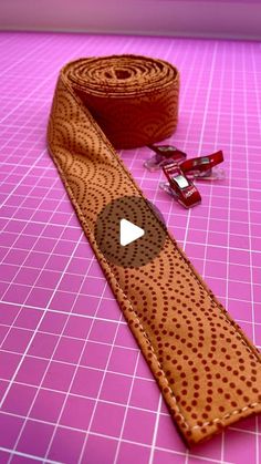 a brown tie sitting on top of a pink counter next to a roll of tape