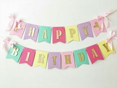 two happy birthday banners with pink, blue and yellow ribbons on them are hanging from the wall