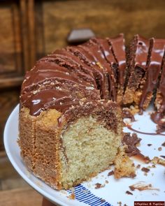 a cake with chocolate frosting on a white plate next to a slice missing from it