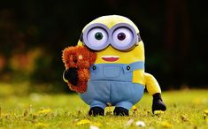 a minion holding a teddy bear in the grass