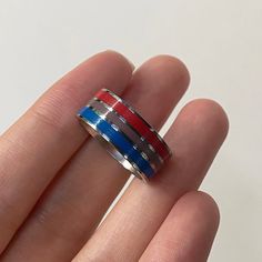 a man's hand is holding a ring with red, white and blue stripes