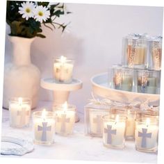 several lit candles sitting on a table next to a vase with flowers