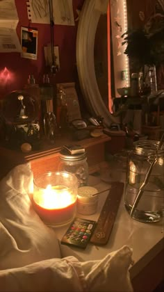 there is a candle on the table next to some jars and other things in front of it