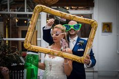 a man and woman are holding up a frame with sunglasses on their faces as they pose for the camera