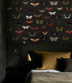 a bed in a bedroom next to a wall with butterflies on it and a lamp