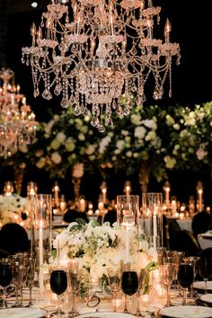 an elegant table setting with candles, flowers and crystal chandelier hanging from the ceiling