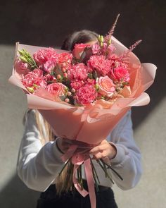 a woman holding a bouquet of pink flowers