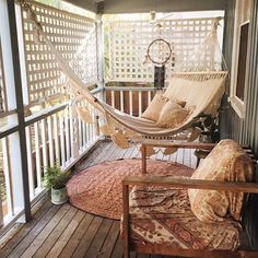 a hammock hanging from the side of a porch next to a chair and rug