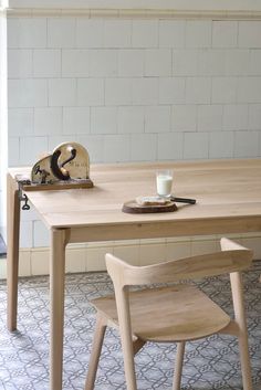 a wooden table with two chairs next to it and a white brick wall in the background