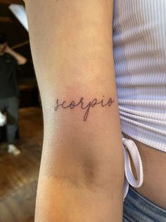 a woman's arm with the word scorpi on it, and her name in cursive font