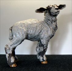 a statue of a sheep standing on top of a black floor next to a white wall