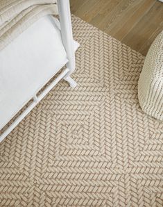 a white bed sitting next to a beige rug on top of a hard wood floor