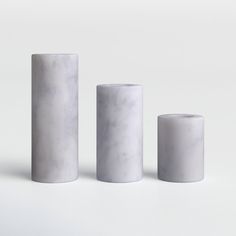 three white marble vases sitting next to each other