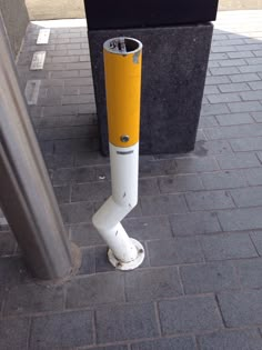 there is a yellow and white pole on the sidewalk