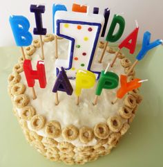 a birthday cake with candles that spell out the word happy on it and some pretzels