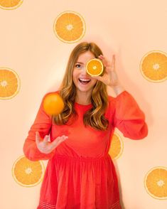 a woman holding two oranges up to her face