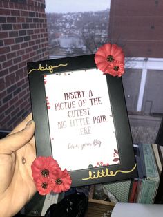 a person holding up a frame with flowers on it