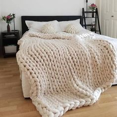 a bed with white blankets and pillows on top of it next to a wooden floor