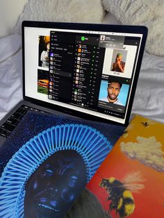 an open laptop computer sitting on top of a bed next to a book and teddy bear