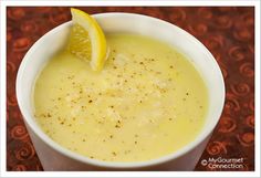 a white bowl filled with soup and a lemon wedge