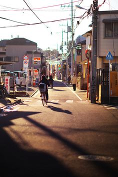 a person riding a bike down the middle of a street with power lines above them