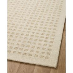 a white rug with brown dots on the bottom and beige flooring in the middle