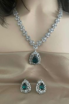 Elevate your style with our Emerald Green Silver Diamond Necklace Set, featuring high-quality CZ diamonds and matching studs. This exquisite set is perfect for engagement parties, cocktail events, and weddings, adding a touch of elegance to any occasion. The rich emerald green stones complement the sparkling silver diamonds, creating a captivating ensemble that matches effortlessly with your wardrobe. Embrace sophistication and glamour with this stunning jewelry set, designed to enhance your special moments.  All our products are crafted using traditional skills from our rich heritage. The manual nature of these crafts means that irregularities or variations may inherent in the handcrafting process. Luxury Green Diamond Bridal Necklace, Luxury Green Bridal Necklace With Cutdana, Luxury Heavy Traditional Emerald Necklace, Green Luxury Temple Necklace For Formal Events, Bridal Necklace With Sparkling Stones For Party, Party Bridal Necklace With Sparkling American Diamonds, Bollywood Style American Diamond Jewelry Sets For Party, Hand Set American Diamond Bridal Necklace For Party, Party Bridal Necklace With Hand Set American Diamonds