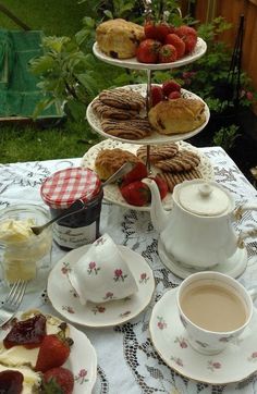 three tiered trays filled with pastries and strawberries on a table outside