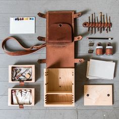 an assortment of crafting supplies laid out on top of a wooden box with leather handles