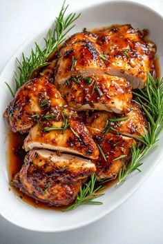 sliced chicken with sauce and herbs in a white bowl