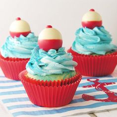 three cupcakes with blue and red frosting sitting on top of a towel