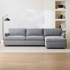 a gray couch sitting on top of a hard wood floor next to a white wall