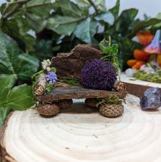 a small wooden bench sitting on top of a tree stump next to rocks and plants