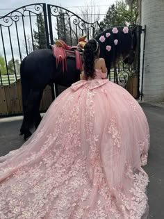 a woman in a pink dress standing next to a horse wearing a bridal gown