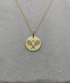 a tennis racket and ball pendant on a gold chain