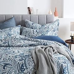 a bed with blue and white comforters in a bedroom next to a night stand