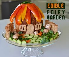 an edible fairy garden is displayed on a cake plate