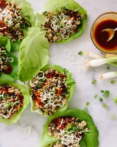 small lettuce cups filled with various toppings next to a cup of dipping sauce