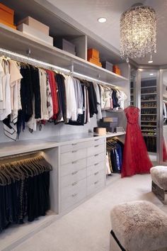 a walk in closet filled with lots of clothes and shoes next to a chandelier