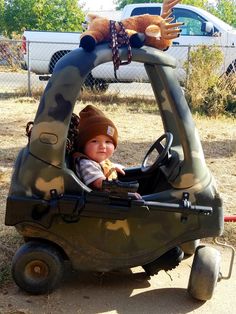 a baby in a toy car with a stuffed animal on top of it's head