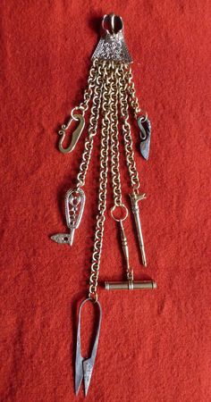 an assortment of metal objects on a red surface, including scissors and other items that are attached to the chain