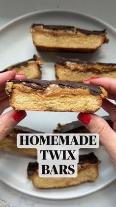 two hands holding a half eaten sandwich on a plate with the words homemade twix bars